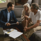 active senior couple discussing with real estate agent living room 85x85